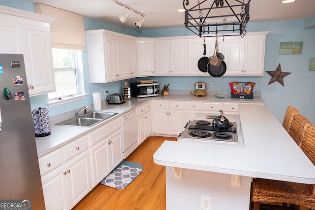 kitchen featuring stainless steel appliances, white cabinetry, decorative light fixtures, and sink