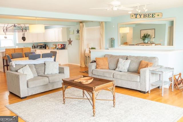 living room with ceiling fan with notable chandelier and light hardwood / wood-style floors