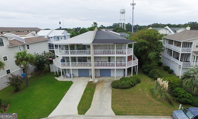 rear view of property featuring a balcony, a yard, and a garage