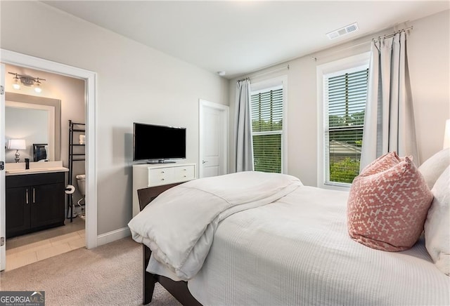 bedroom featuring light carpet, ensuite bath, and sink