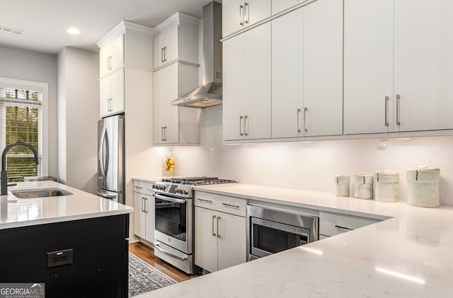 kitchen featuring sink, dark wood-type flooring, wall chimney range hood, white cabinetry, and stainless steel appliances