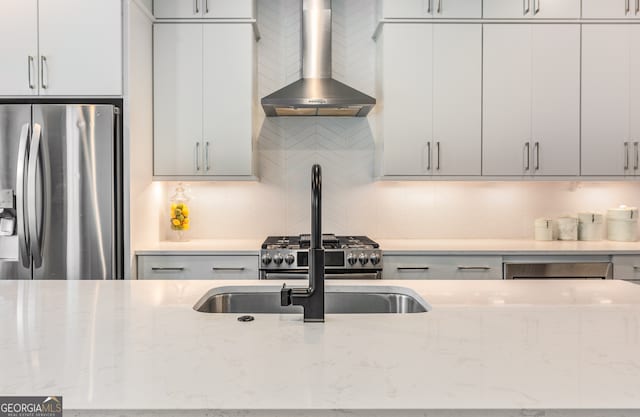 kitchen featuring light stone countertops, wall chimney range hood, stainless steel appliances, and tasteful backsplash