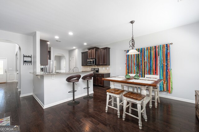 kitchen featuring dark brown cabinetry, kitchen peninsula, dark hardwood / wood-style floors, and stainless steel appliances