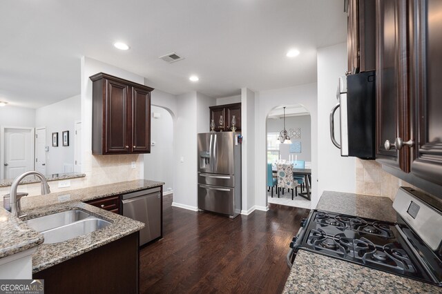 kitchen featuring light stone counters, sink, backsplash, stainless steel appliances, and dark hardwood / wood-style floors