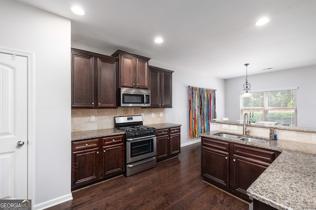 kitchen with hanging light fixtures, light stone counters, dark hardwood / wood-style flooring, stainless steel appliances, and sink