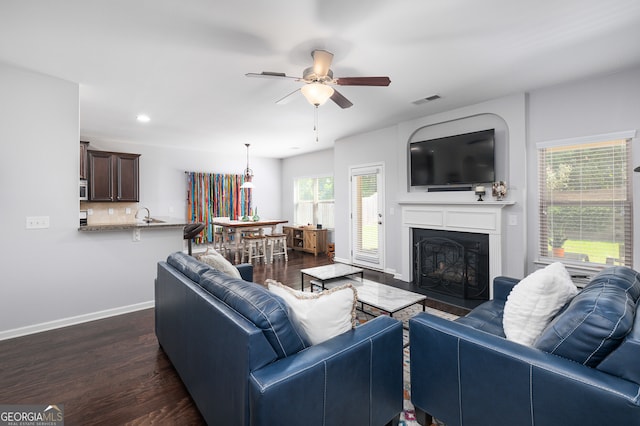 living room featuring ceiling fan, dark hardwood / wood-style floors, plenty of natural light, and sink