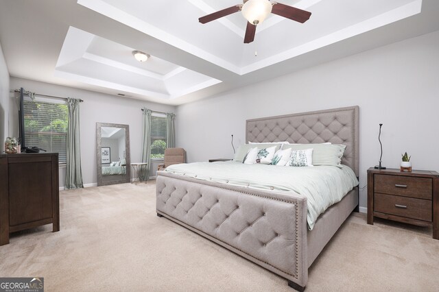 carpeted bedroom with ceiling fan and a raised ceiling