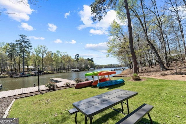 view of community with a lawn, a dock, and a water view