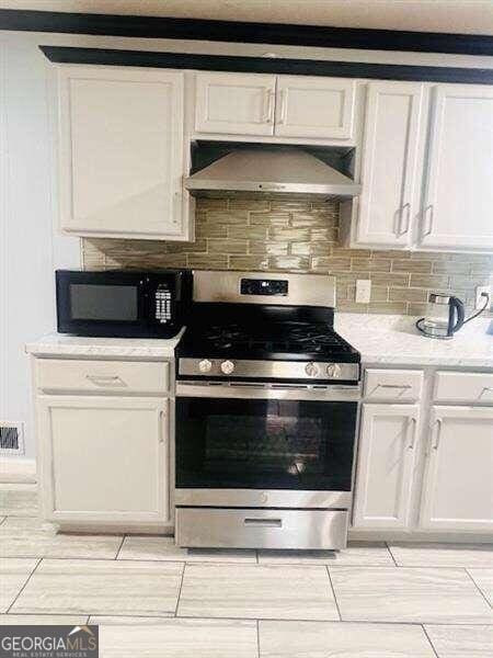 kitchen featuring white cabinets, backsplash, stainless steel range, and wall chimney exhaust hood