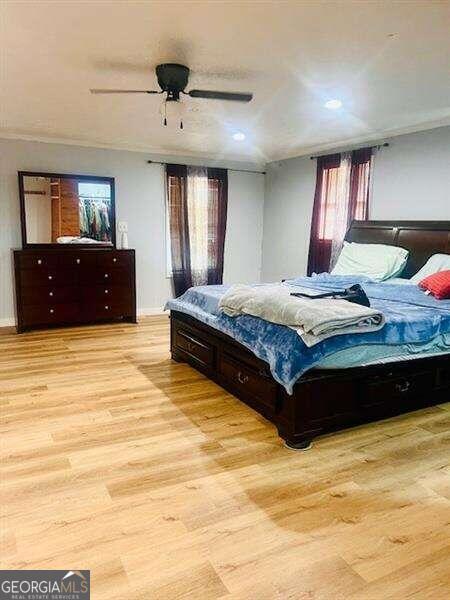 bedroom with ceiling fan, light wood-type flooring, and multiple windows