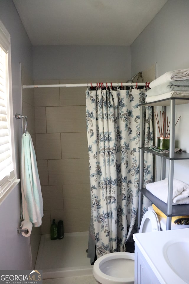 bathroom with a shower with shower curtain, vanity, toilet, and a healthy amount of sunlight