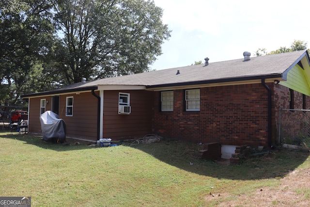 rear view of house featuring cooling unit and a lawn