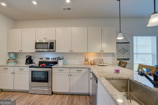 kitchen featuring white cabinetry, stainless steel appliances, and hanging light fixtures