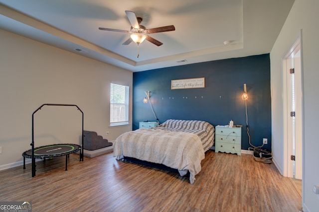 bedroom featuring ceiling fan, a tray ceiling, and hardwood / wood-style flooring