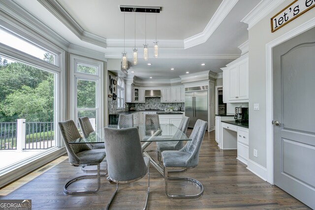 dining space with a tray ceiling, ornamental molding, sink, and dark hardwood / wood-style floors