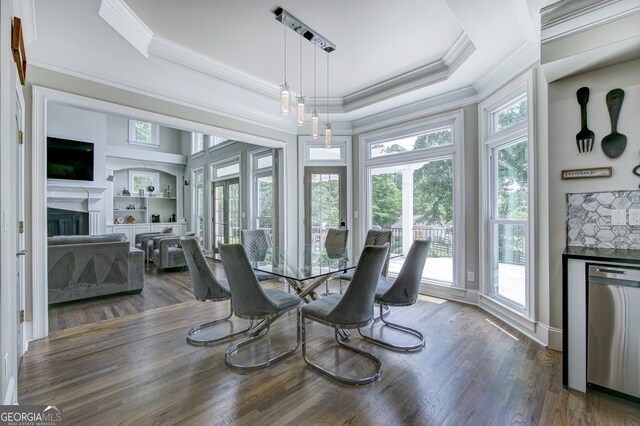 dining room featuring dark wood-type flooring, a tray ceiling, and ornamental molding