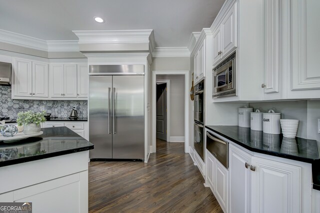 kitchen with white cabinetry, dark wood-type flooring, built in appliances, and ornamental molding