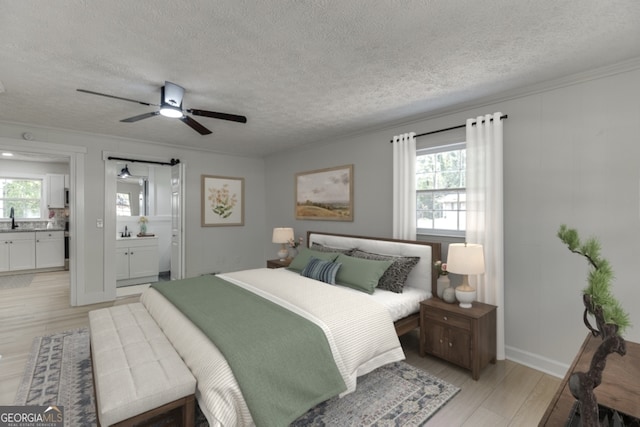 bedroom featuring a textured ceiling, light wood-type flooring, ensuite bathroom, and ceiling fan