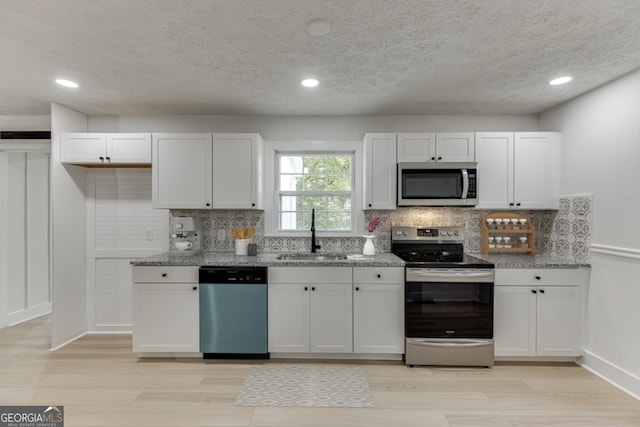 kitchen with light stone counters, white cabinetry, sink, and appliances with stainless steel finishes