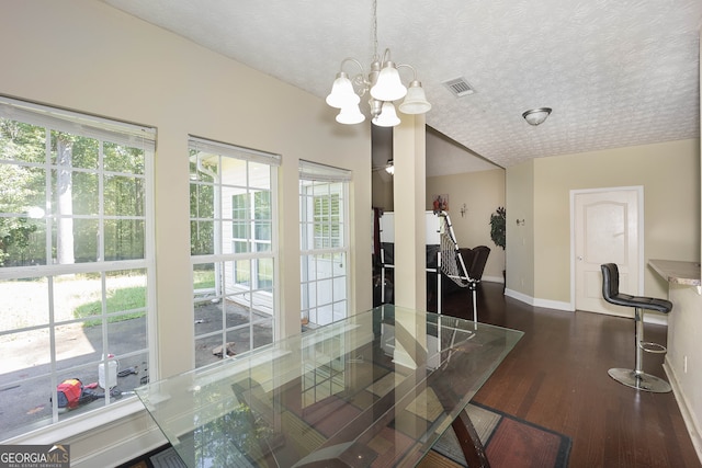 dining room with dark wood-type flooring, a notable chandelier, and a textured ceiling