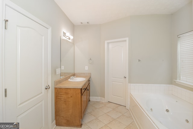 bathroom featuring tile patterned flooring, tiled tub, and vanity