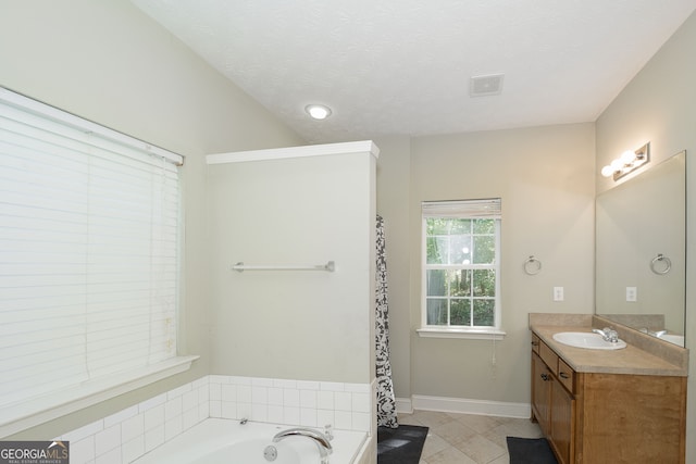 bathroom featuring a textured ceiling, a tub, vanity, and tile patterned floors