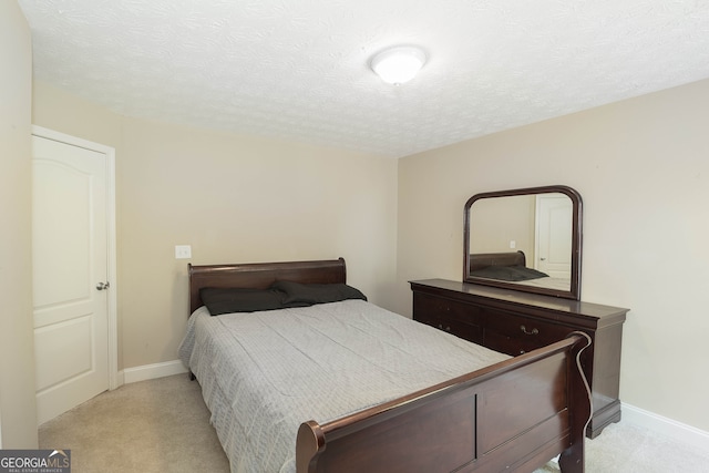 bedroom with a textured ceiling and light colored carpet