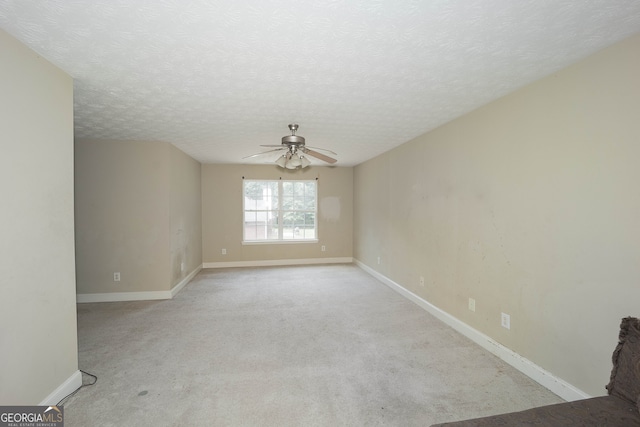 spare room featuring ceiling fan, light colored carpet, and a textured ceiling