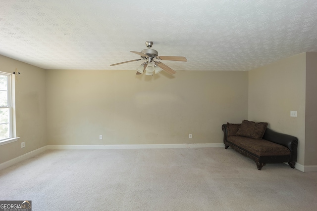 unfurnished room with a textured ceiling, light colored carpet, and ceiling fan