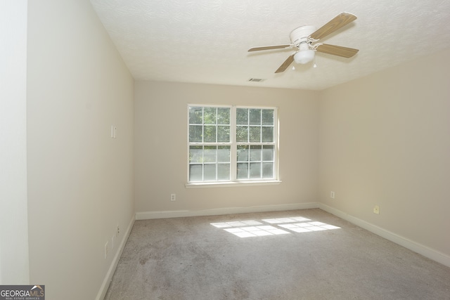 empty room with a textured ceiling, light colored carpet, and ceiling fan