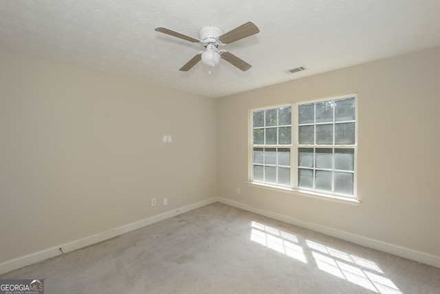 unfurnished room with a textured ceiling, ceiling fan, and light carpet