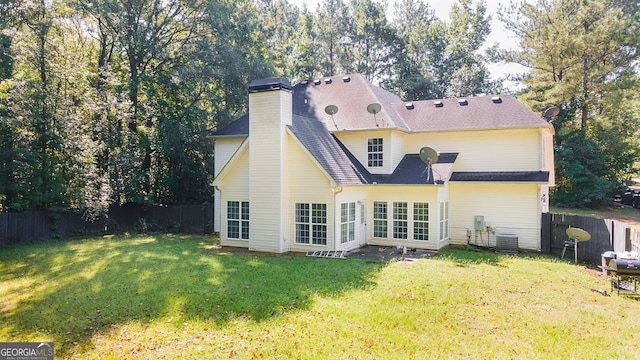 rear view of house with central air condition unit and a lawn