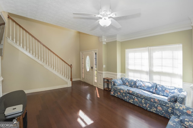 living room with dark wood-type flooring, ceiling fan, a textured ceiling, and ornamental molding