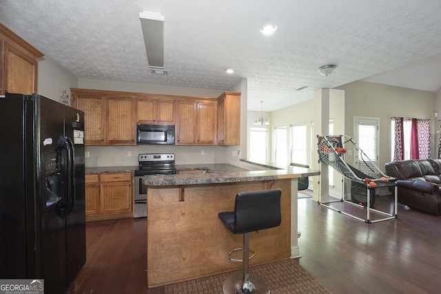 kitchen with black appliances, a wealth of natural light, kitchen peninsula, and a breakfast bar