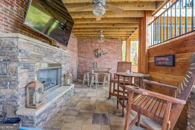 view of patio with a bar, an outdoor stone fireplace, and ceiling fan