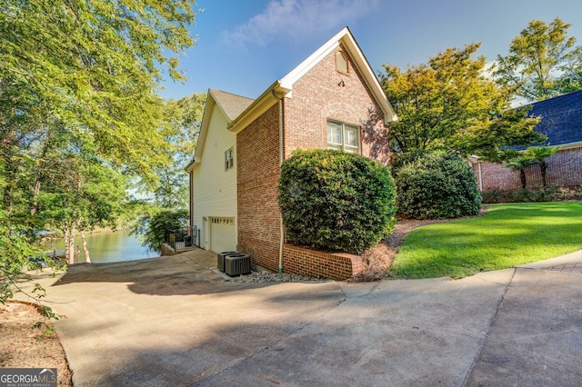 view of property exterior featuring a garage, a water view, cooling unit, and a lawn