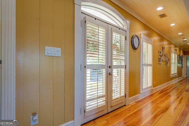 doorway featuring french doors, a healthy amount of sunlight, ornamental molding, and light hardwood / wood-style flooring