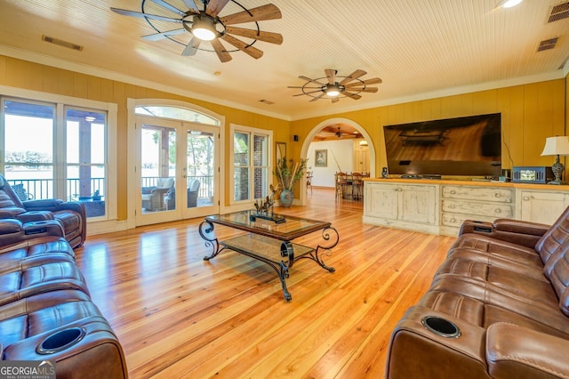 living room with light wood-type flooring, ceiling fan, ornamental molding, and french doors