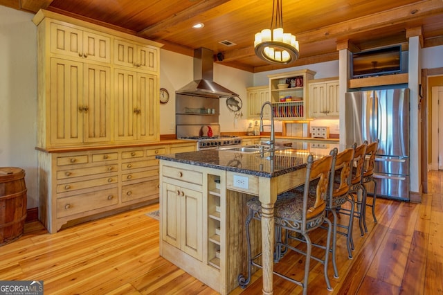 kitchen featuring light wood-type flooring, exhaust hood, a breakfast bar, appliances with stainless steel finishes, and a center island with sink