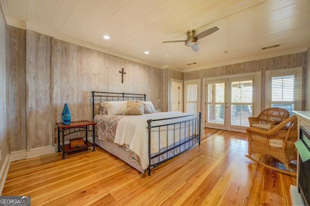 bedroom featuring ceiling fan, wooden walls, and light hardwood / wood-style floors