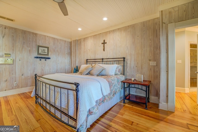 bedroom with hardwood / wood-style flooring, ceiling fan, and wooden walls