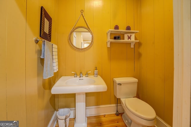 bathroom with toilet, wood-type flooring, and wood walls