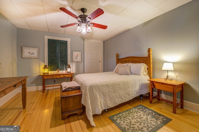 bedroom with a paneled ceiling, ceiling fan, and hardwood / wood-style floors