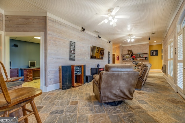 living room featuring a healthy amount of sunlight, wood walls, and ceiling fan