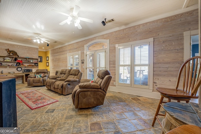 living room with crown molding, ceiling fan, and wooden walls