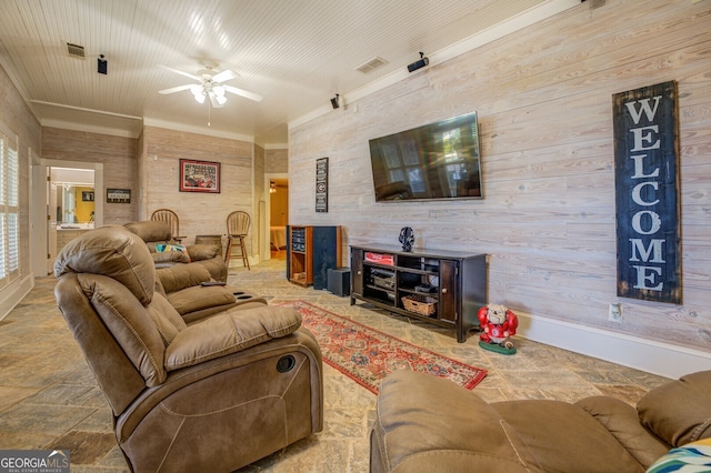 living room featuring ornamental molding, wood walls, and ceiling fan