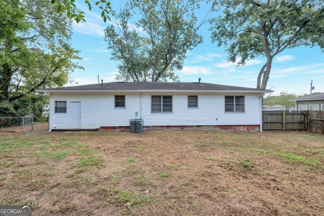 rear view of house with central AC unit and a lawn