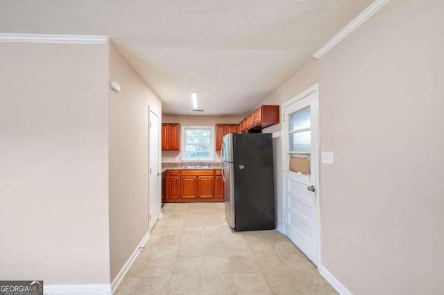 kitchen featuring ornamental molding, stainless steel fridge, a textured ceiling, and sink