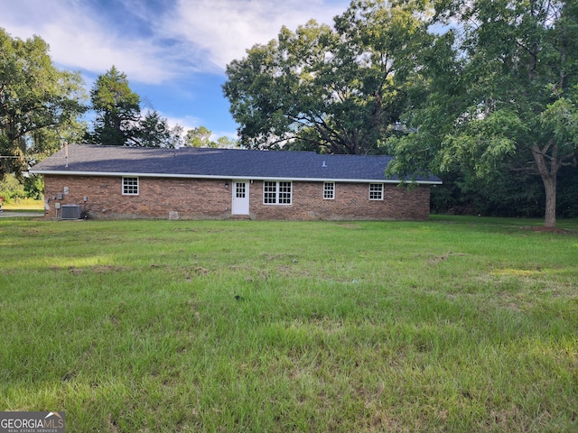 rear view of house with central AC unit and a yard