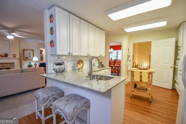 kitchen featuring light stone counters, kitchen peninsula, sink, and ceiling fan